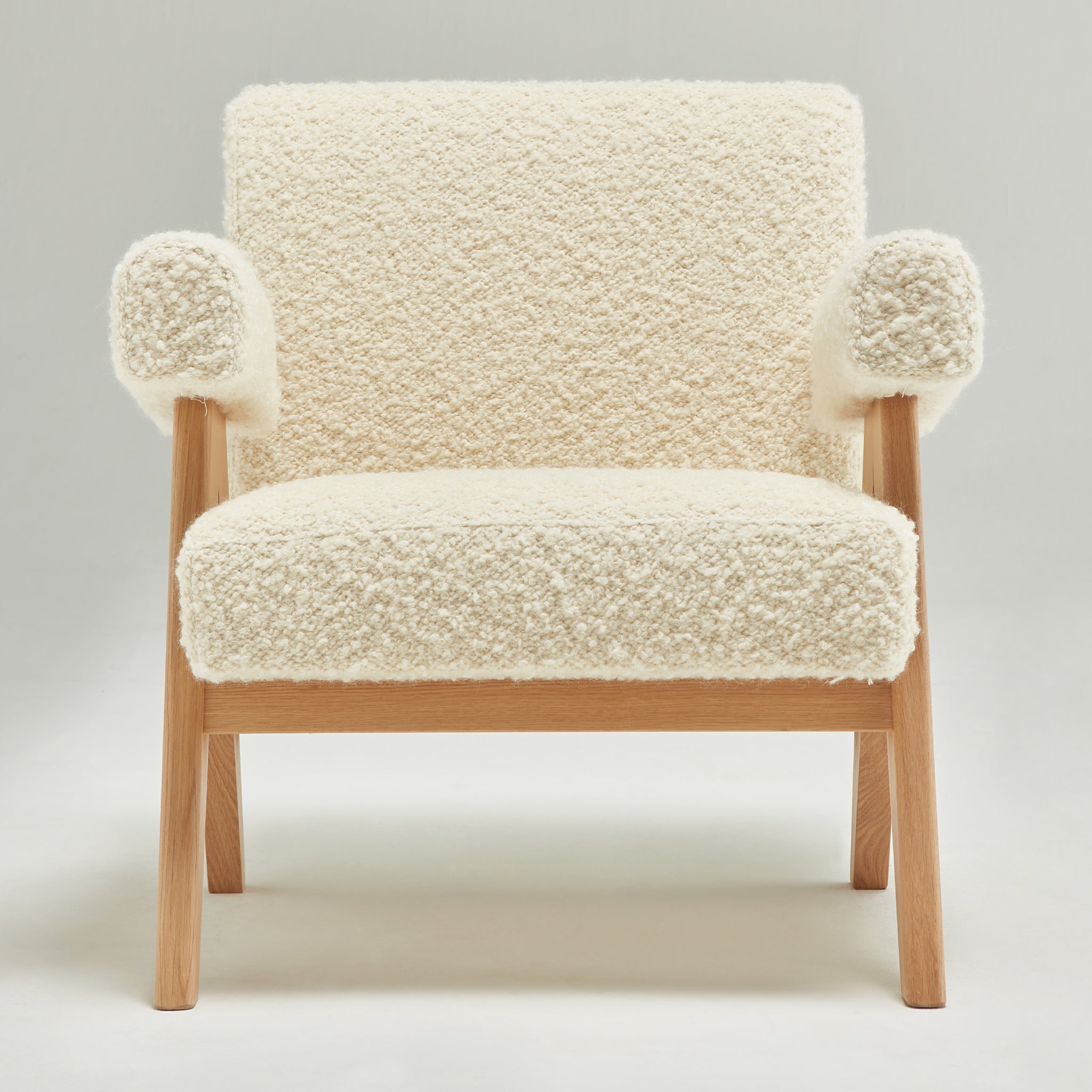 Front view of an authentic chandigarh lounge chair, pierre jeanneret era, natural oak frame, pierre frey opio naturel boucle upholstery, by Klarel #K35-33