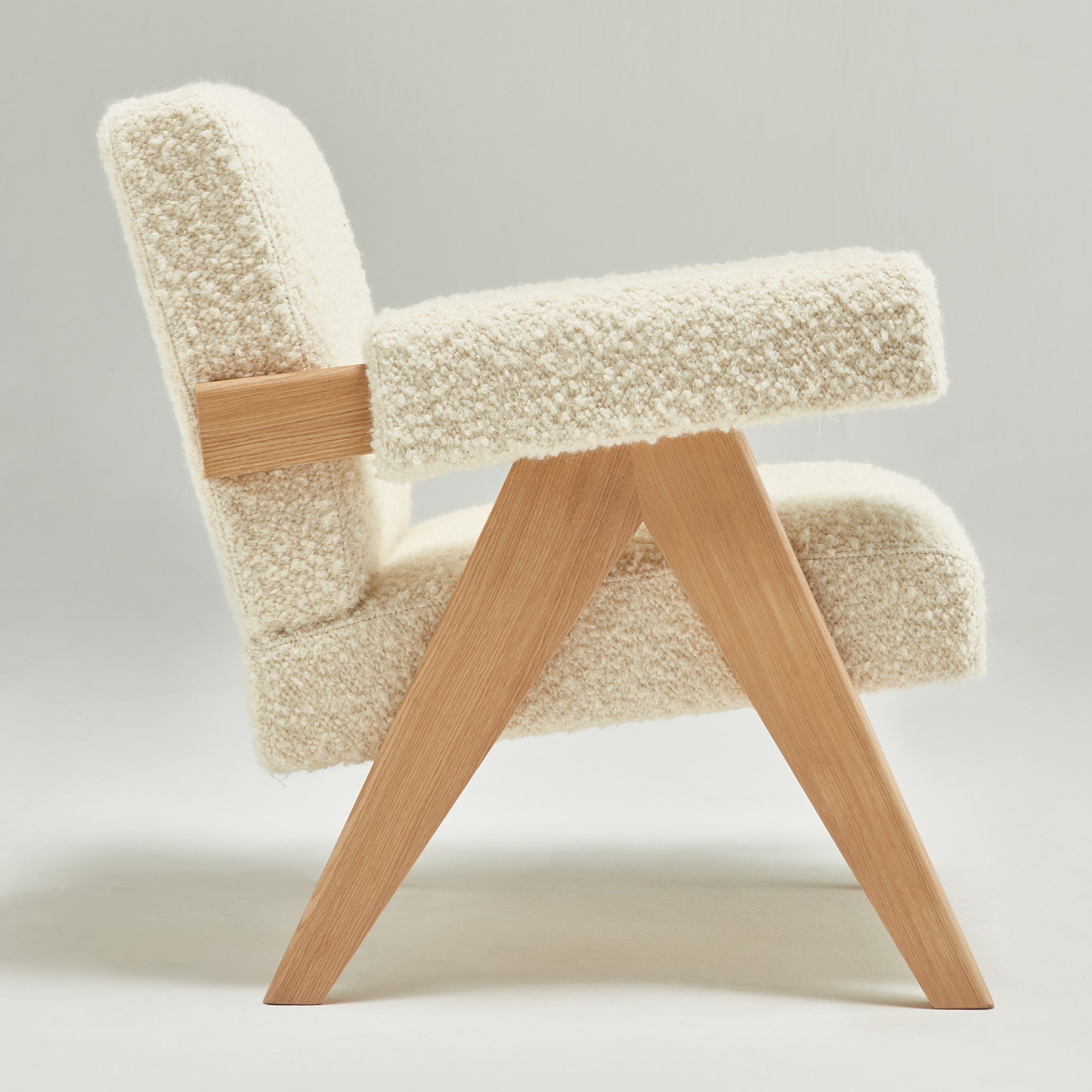 Side view of an authentic chandigarh lounge chair, pierre jeanneret era, natural oak frame, pierre frey opio naturel boucle upholstery, by Klarel #K35-33